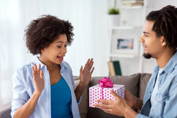 Casal feliz com caixa de presente em casa — Fotografia de Stock