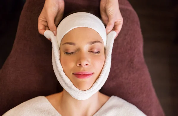 Donna con massaggio viso con asciugamano al centro benessere — Foto Stock