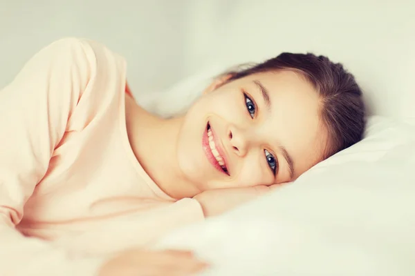 Menina sorridente feliz deitado acordado na cama em casa — Fotografia de Stock