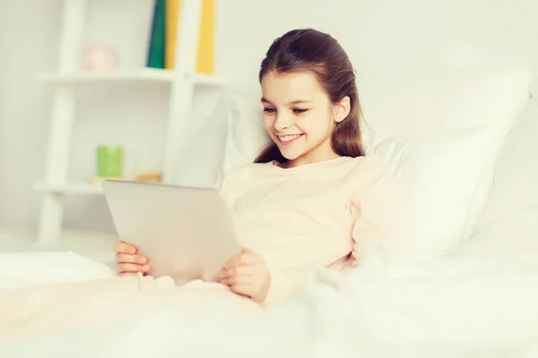 Chica feliz acostada en la cama con la tableta PC en casa — Foto de Stock