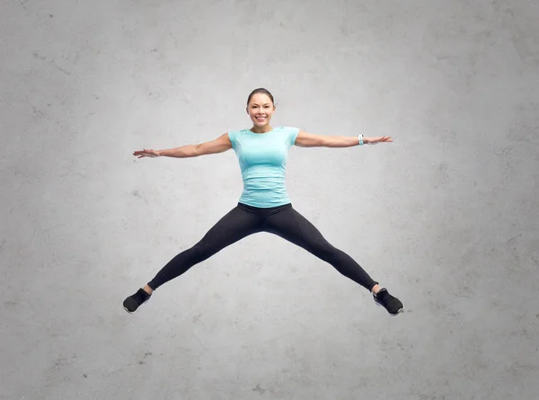 Gelukkig glimlachen sportieve jonge vrouw springen in de lucht — Stockfoto