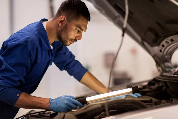 Monteur man met lamp repareren auto bij workshop — Stockfoto