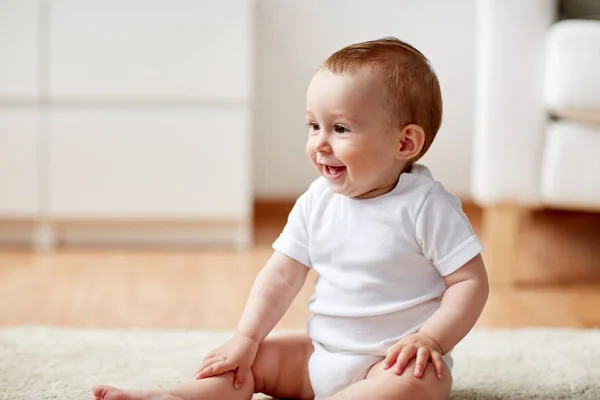 Glad liten pojke eller flicka sitter på golvet hemma — Stockfoto