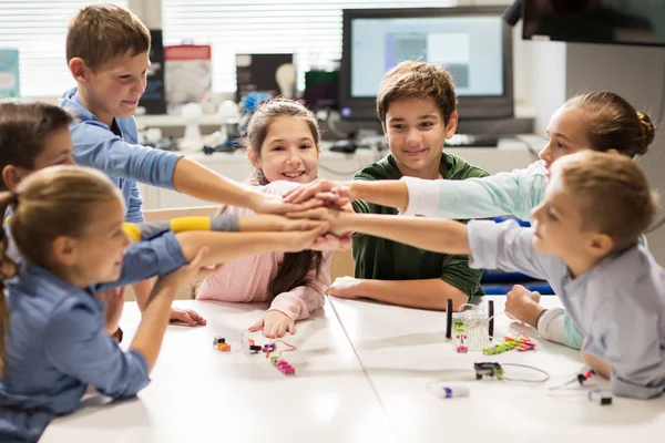 Happy children holding hands at robotics school — Stock Photo, Image