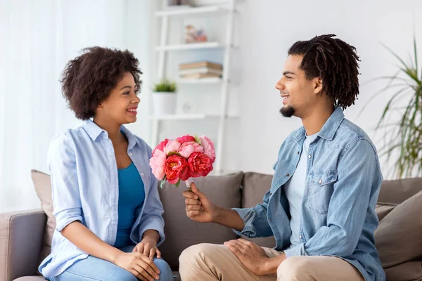 Happy couple with bunch of flowers at home — Stock Photo, Image