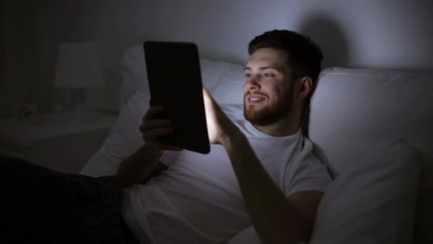 Jonge man met tablet pc in bed huis slaapkamer — Stockvideo