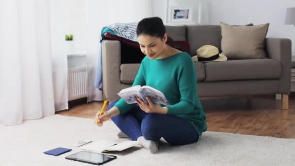 Woman with city guide and travel bag at home — Stock Video