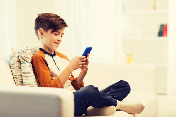 Chlapec s smartphonem smskování nebo hraní doma — Stock fotografie
