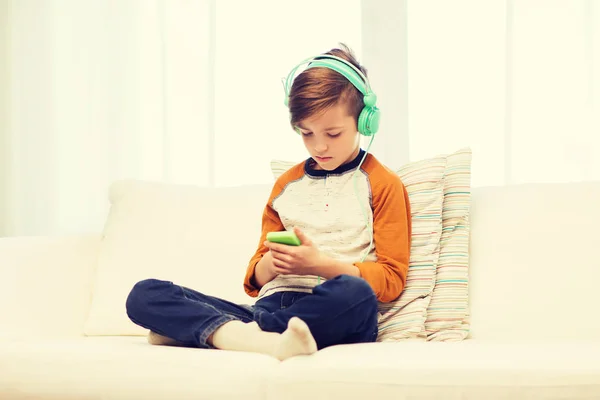 Pojke med smartphone och hörlurar hemma — Stockfoto