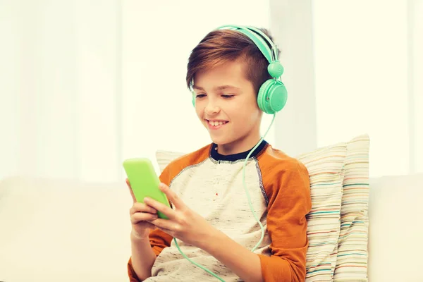 Happy boy met smartphone en hoofdtelefoon thuis — Stockfoto