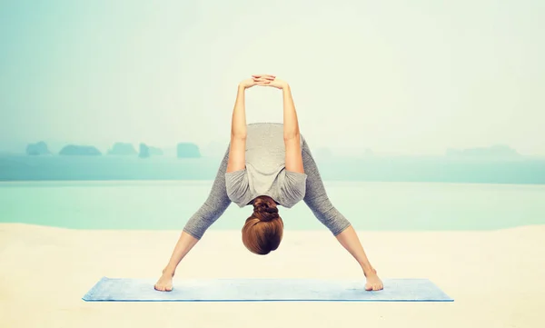 Vrouw maken yoga wide-legged forward bend op mat — Stockfoto