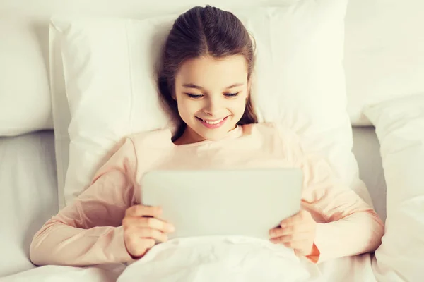 Chica feliz acostada en la cama con la tableta PC en casa —  Fotos de Stock