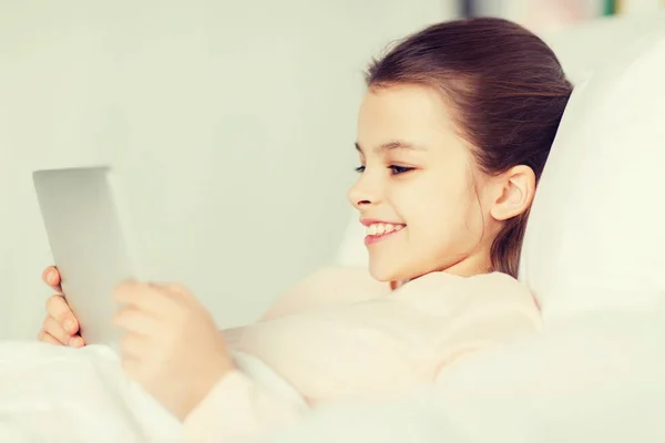 Happy girl lying in bed with tablet pc at home — Stock Photo, Image