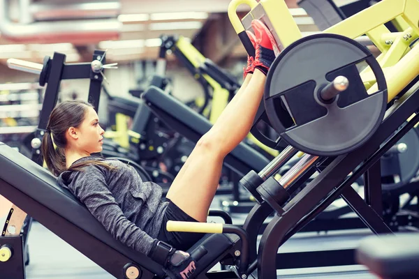 Woman flexing muscles on leg press machine in gym — Stock Photo, Image