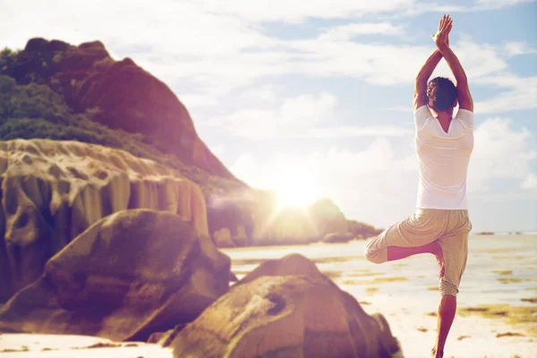 Man mediterar i yogaställning träd över stranden — Stockfoto