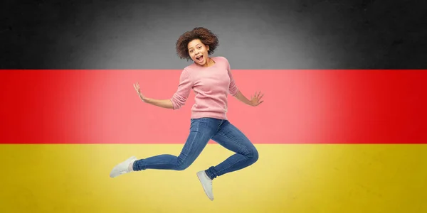 Mujer afroamericana saltando sobre bandera alemana — Foto de Stock