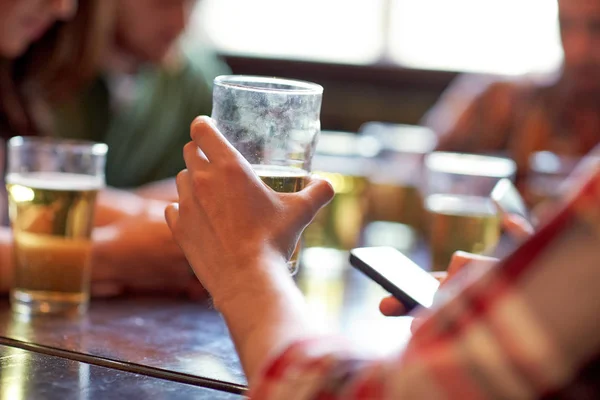 Homem com cerveja e smartphones no bar ou pub — Fotografia de Stock