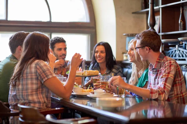 Amigos felizes comendo e bebendo no bar ou pub — Fotografia de Stock