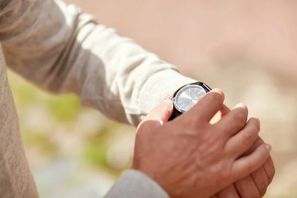 Senior memeriksa waktu pada jam tangan luar ruangan — Stok Foto