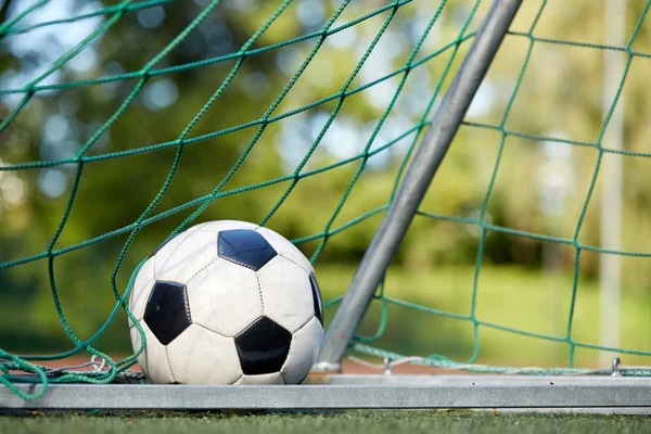 Bola de futebol no gol net no campo de futebol — Fotografia de Stock