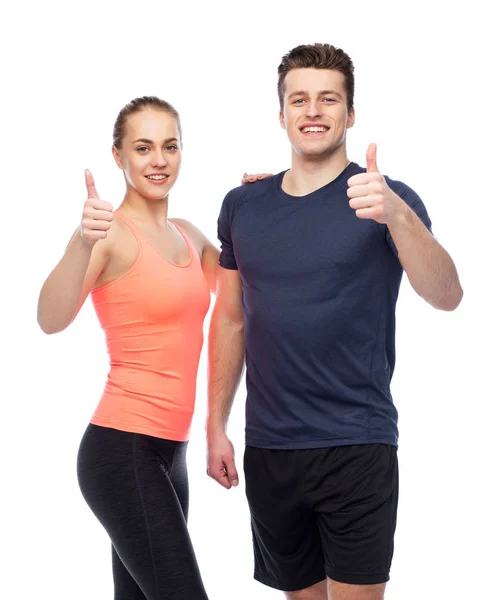 Happy sportive man and woman showing thumbs up — Stock Photo, Image