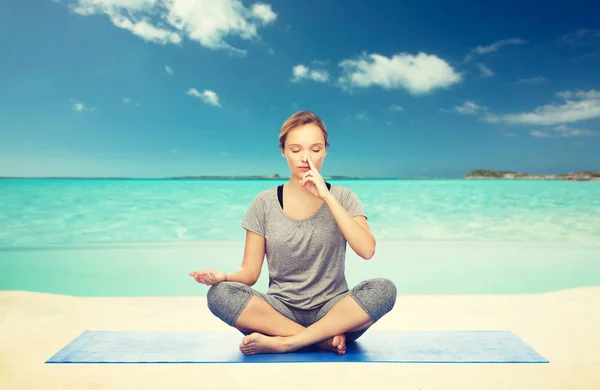 Женщина медитирует в позе йоги лотоса на пляже — стоковое фото