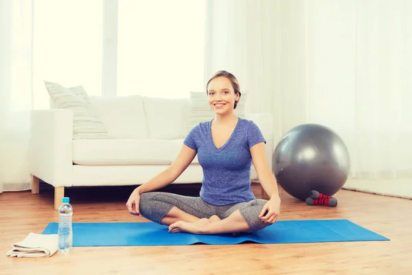 Vrouw maken yoga in lotus pose op de mat — Stockfoto