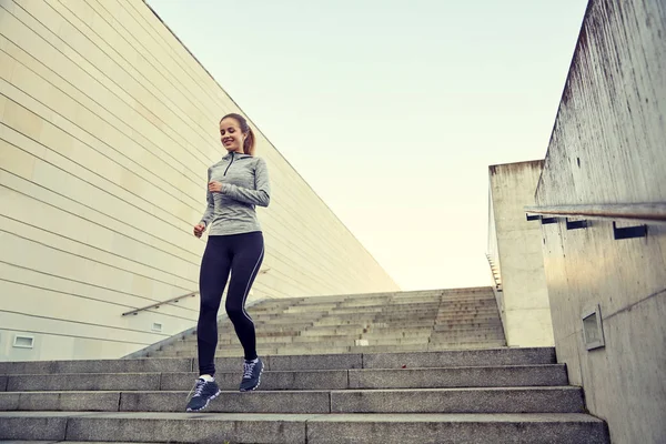 Happy sporty woman running downstairs in city — Stock Photo, Image