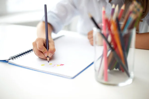 Девочка рисует цветным карандашом в блокноте — стоковое фото