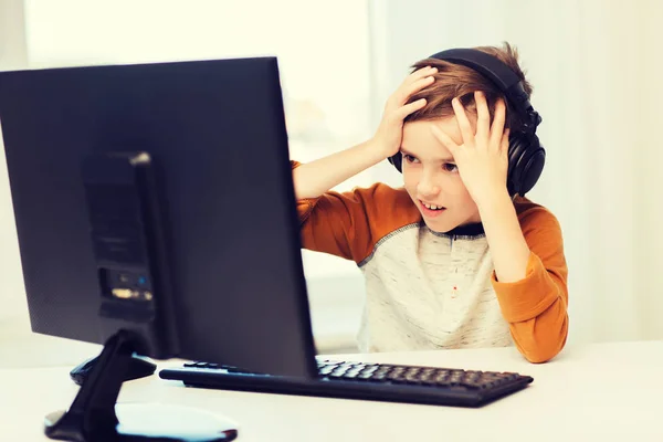 Terrified boy with computer and headphones at home — Stock Photo, Image