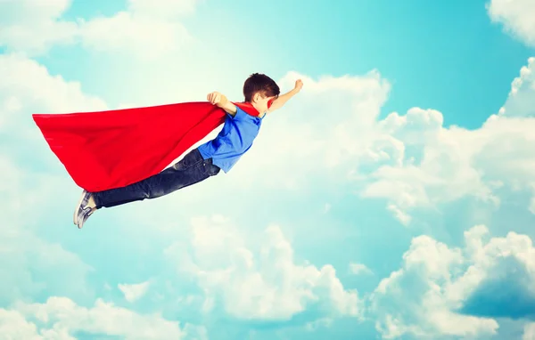 Niño en capa de superhéroe rojo y máscara volando sobre el cielo — Foto de Stock