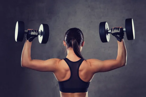 Молодая женщина сгибает мышцы гантелями в спортзале — стоковое фото
