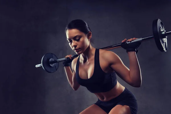 Young woman flexing muscles with barbell in gym — Stock Photo, Image