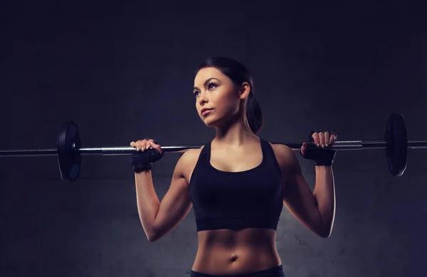 Jeune femme flexion des muscles avec haltère dans la salle de gym — Photo