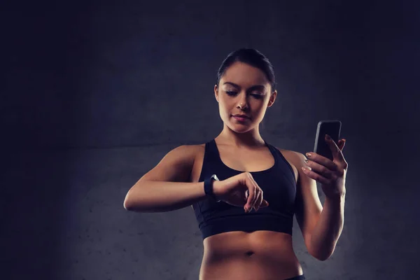 Frau mit Pulsuhr und Smartphone im Fitnessstudio — Stockfoto