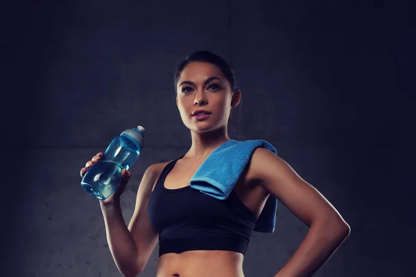 Donna con asciugamano acqua potabile da bottiglia in palestra — Foto Stock