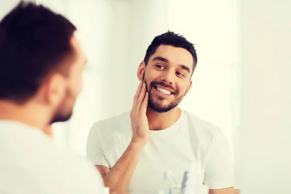 Happy young man looking to mirror at home bathroom — Stock Photo, Image