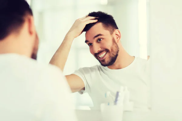 Χαρούμενος νεαρός άνδρας ψάχνει να καθρέφτη στο σπίτι μπάνιο — Φωτογραφία Αρχείου