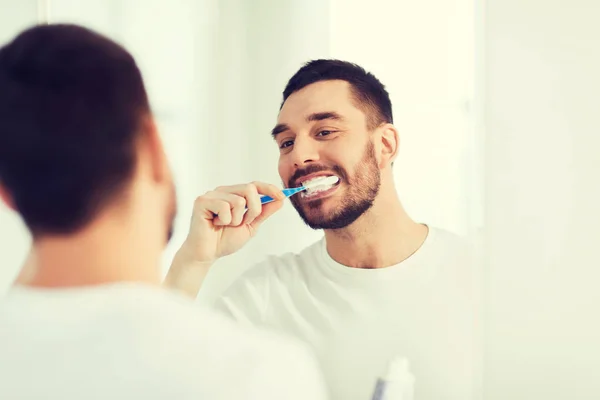 man with toothbrush cleaning teeth at bathroom