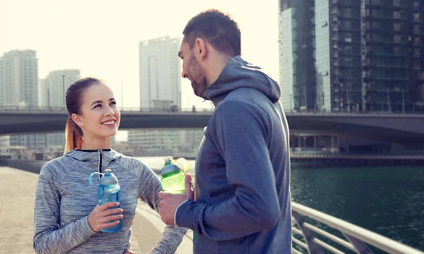 Smiling couple with bottles of water in city — Stock Photo, Image