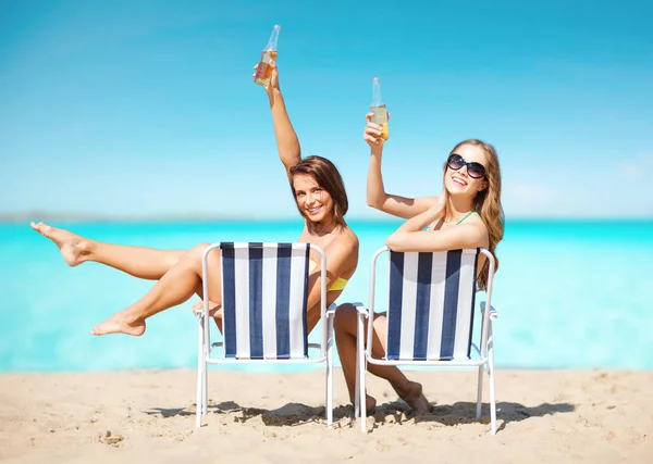 Mujeres jóvenes felices con bebidas tomando el sol en la playa — Foto de Stock