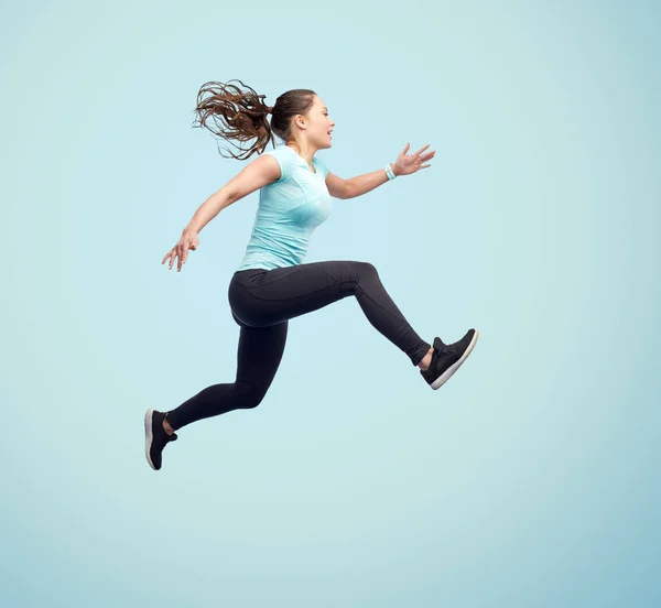 Gelukkig glimlachen sportieve jonge vrouw springen in de lucht — Stockfoto