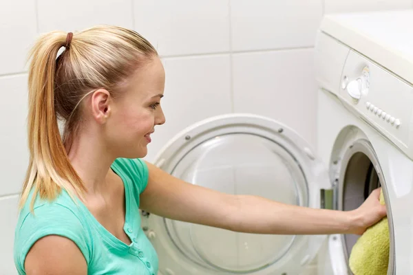Mujer feliz poniendo la ropa en la lavadora en casa —  Fotos de Stock