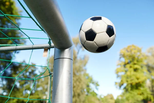 Bola de futebol voando em futebol gol net no campo — Fotografia de Stock