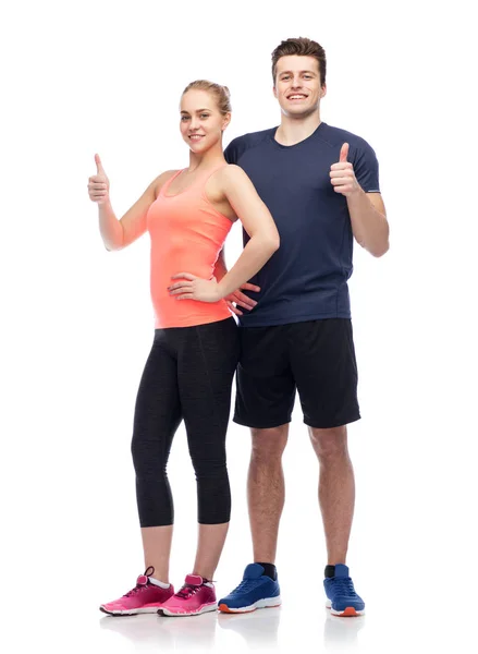 Happy sportive man and woman showing thumbs up — Stock Photo, Image