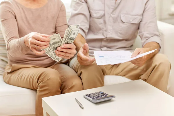 Casal sênior com dinheiro e calculadora em casa — Fotografia de Stock