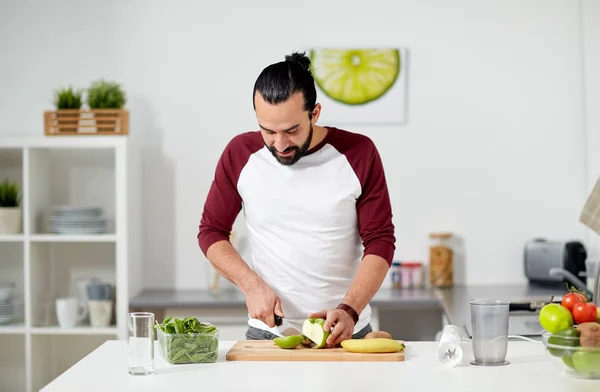 Hombre con licuadora y cocina de frutas en la cocina casera —  Fotos de Stock