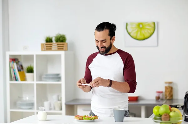 Hombre fotografiando comida por teléfono inteligente en casa —  Fotos de Stock