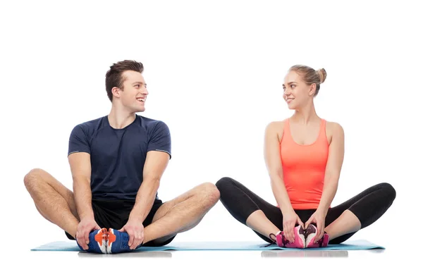 Gelukkig sportieve man en vrouw zitten op matten — Stockfoto