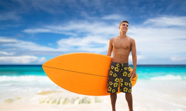 Plajda sörf tahtası ile gülümseyen genç adam — Stok fotoğraf